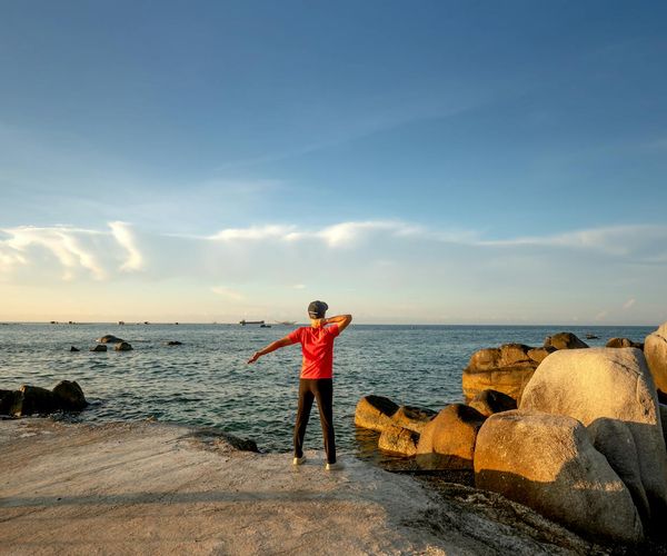 Silhouette of a woman stretching during sunrise, symbolizing renewed energy.